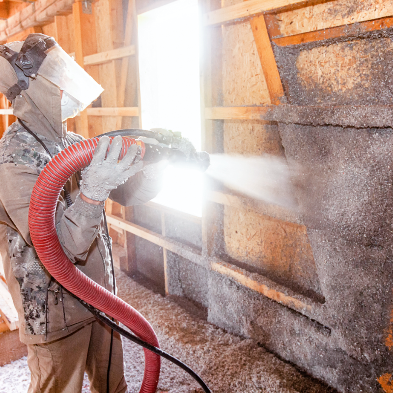 A contractor blowing insulation into a home
