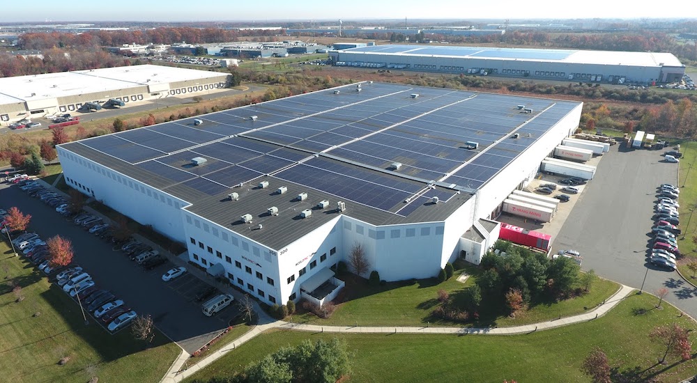 A large warehouse building with solar panels, an energy-efficient roofing material on top