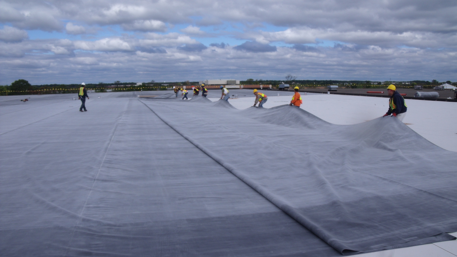 Technicians installing a membrane commercial roofing system