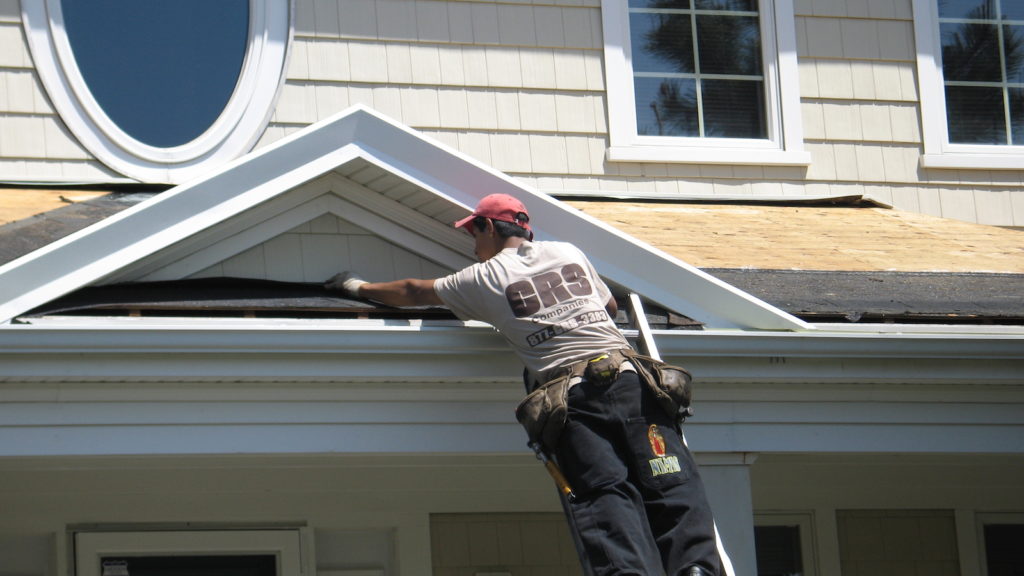 A certified roofing and siding contractor working on the soffit of a home.