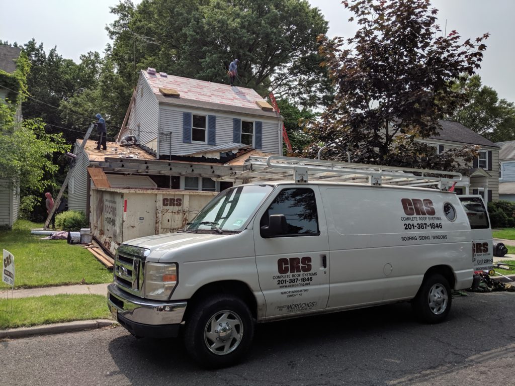 A CRS van in front of a house in need of a roofing and siding contractor