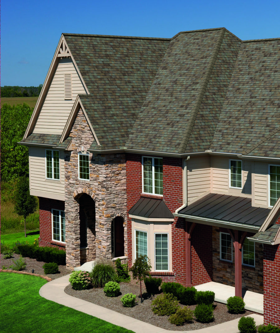 A photograph showing a complimentary Owens Corning shingle color on a large brick and stone home